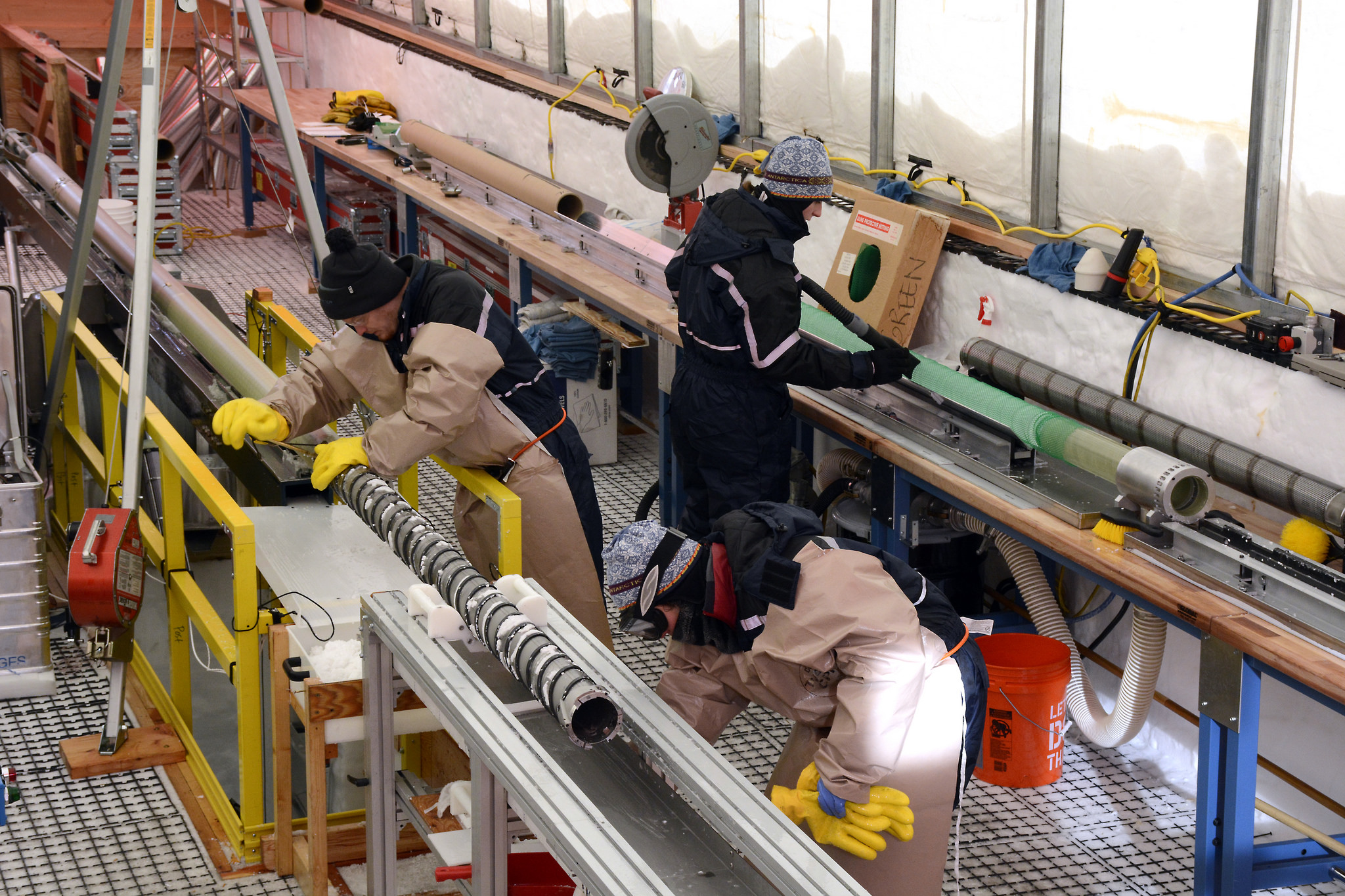 Science team members work in the South Pole Ice Core (SPICEcore) drilling tent cleaning the Intermediate Depth Drill and measuring ice cores. Credit: Peter Rejcek, NSF
